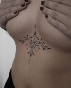 a woman's stomach with an intricate tattoo on the side and her hands over her belly