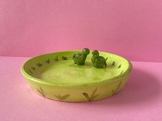 two green teddy bears sitting in a yellow bowl