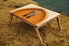 a wooden table sitting on top of a sandy beach next to the ocean and water