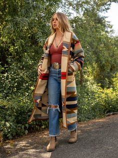 Wyeth Trail Long Stadium Coat Our Wyeth Trail Long Stadium Coat will keep you covered from top to below the knee. Made from the Pendleton Wyeth Trail wool blanket, the warm earth tone colors are easy to wear. Wear it open or close at the waist with a toggle. Designed for a slightly oversized fit and look. The Wyeth Trail blanket reflects warm, harmonious colors of ancient corn varieties patterned in rows similar to ancient Native American gardens. Arrows point in two directions, the past and the Blanket Coat Outfit, Western Inspired Fall Outfits, Big Sur Style Fashion, Native Clothing Women Style, Native American Modern Fashion, Fall 2024 Western Fashion Trends, Sedona Style Fashion, Elegant Bohemian Fashion, Western Blazers Women