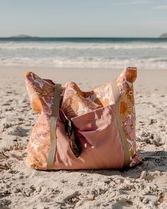 an orange and pink bag sitting on top of a sandy beach next to the ocean