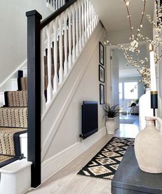 an entry way with stairs and vases on the floor