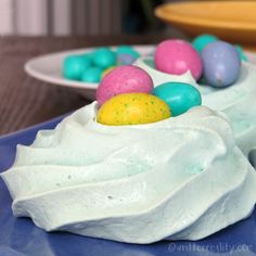 there is a cake with white frosting and colored eggs on it, sitting on a plate