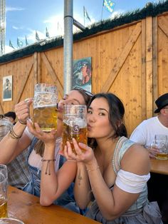 two women are sitting at a table drinking beer