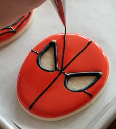 someone is decorating a decorated cookie with icing and black piping on it