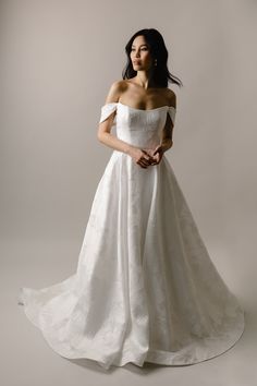 a woman in a white wedding dress posing for the camera with her hands on her hips