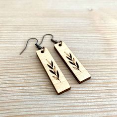 two wooden earrings with black leaves on them