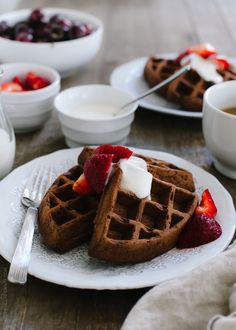 two waffles on a plate with strawberries and whipped cream