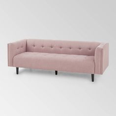 a pink couch sitting on top of a white floor next to a gray wall with black legs