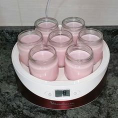 several jars filled with pink liquid sitting on top of a counter next to a clock