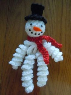 a snowman made out of yarn sitting on top of a wooden table