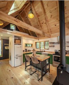 a kitchen with green and white cabinets, wood flooring and an island in the middle