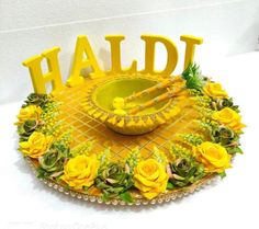 a yellow tray with flowers and letters that spell it's haldii on the table