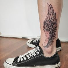 a woman's leg with a wing tattoo on it