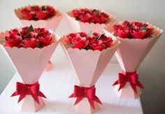 four roses are wrapped in pink paper and tied with red ribbon on top of each other