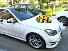 a wedding car decorated with sunflowers and tulle is parked on the street