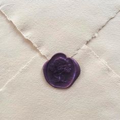 a purple wax seal sitting on top of a piece of paper