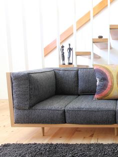 a grey couch sitting on top of a hard wood floor next to a stair case