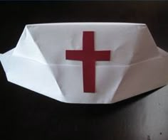 an origami paper bag with a red cross on the front and white background