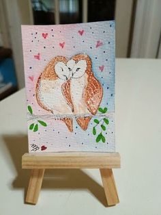 two owls sitting on top of a wooden easel