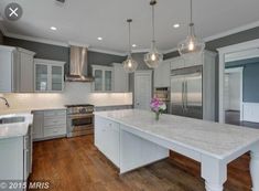 a large kitchen with marble counter tops and stainless steel appliances, along with hardwood floors