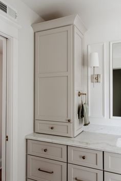 a bathroom with white cabinets and marble counter tops