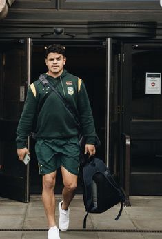 a man with a backpack and tennis shoes walking down the street in front of a building