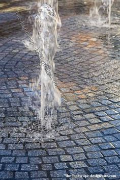 water spouting from the top of a fountain on a cobblestone street