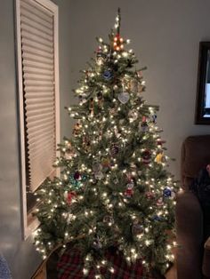 a small christmas tree is lit up in the living room, with lights on it