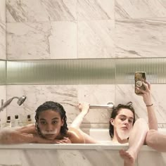 two women taking a bath in a marble tiled bathroom