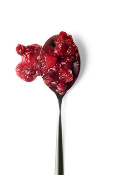 a spoon filled with jelly on top of a white table