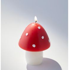 a red and white mushroom candle sitting on top of a table