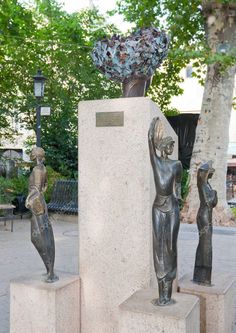 two statues are standing next to each other on cement blocks in front of some trees