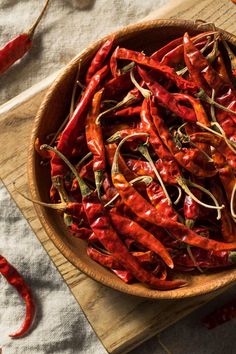 a wooden bowl filled with red peppers on top of a table