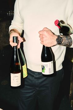 a man holding two bottles of wine in his hands