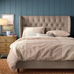 a bedroom with blue walls and an upholstered bed in the center, along with two nightstands