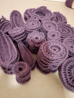 several crocheted pieces of purple yarn on a white counter top next to a pair of shoes