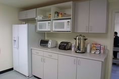 a white refrigerator freezer sitting inside of a kitchen next to a microwave and toaster oven