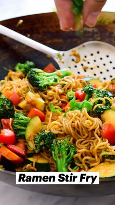 a wok filled with noodles, vegetables and broccoli