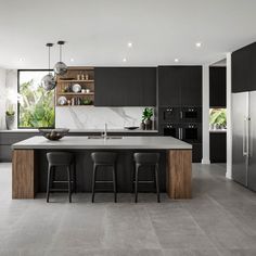 a modern kitchen with black cabinets and marble counter tops, stainless steel appliances and bar stools