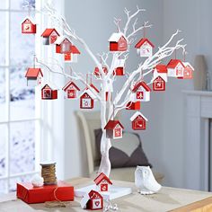 a tree with red and white houses hanging from it