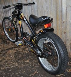 a black and yellow bike parked next to a wooden fence