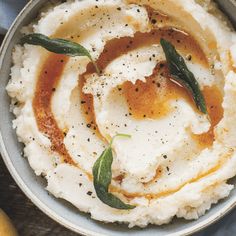 mashed potatoes in a bowl with sage leaves and seasoning on top, ready to be eaten