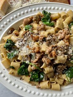 a white plate topped with pasta and spinach covered in meat, cheese and sauce