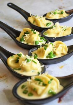 four black spoons filled with food on top of a table