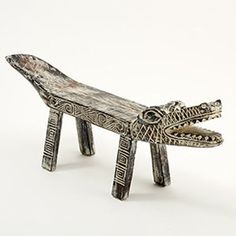 a wooden bench with an alligator's head on the front and legs, made out of metal