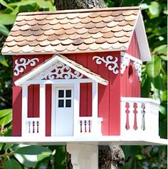 a red and white bird house sitting on top of a tree