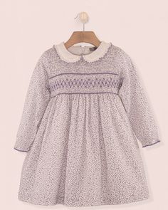 Hand Smocked Perfection. Our Fiorella dress is made in a beautiful French pink floral print fabric and features a fully smocked bodice, long sleeves with elasticated cuffs and a delicate matching ruffle collar. It is fully lined with a fine petticoat. A zip-closure and a matching self tie bow at the back creates a perfect finish. 100% Organic Cotton From France. Fully Lined in Cotton Delicate Machine Wash Cold, Tumble Dry low, Cool Iron, Dry Clean Pink Smocked Dress With Elastic Sleeves For Spring, Spring Pink Smocked Dress With Elastic Sleeves, Elegant Smocked Dress With Floral Print For Daywear, Long Sleeve Smocked Top With Smocked Cuffs For Spring, Spring Purple Smocked Top, Spring Dress With Smocked Back And Bishop Sleeves, Spring Dresses With Smocked Back And Bishop Sleeves, Spring Bishop Sleeve Dress With Smocked Back, Pink Long Sleeve Dress With Smocked Cuffs