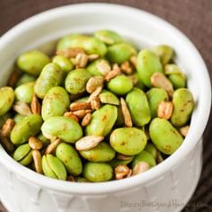 a white bowl filled with green beans and nuts