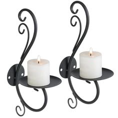 two candles are sitting on the wall next to each other with swirly arms and one candle is lit